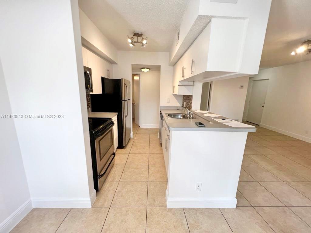 5612 Rock Island Road, Unit 141 Tamarac, FL 33319 - Photo 6 of 22 a kitchen with stainless steel appliances granite countertop a refrigerator a stove top oven and a sink