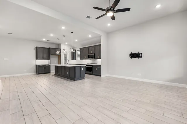 a view of kitchen with kitchen island stainless steel appliances a sink cabinets and wooden floor