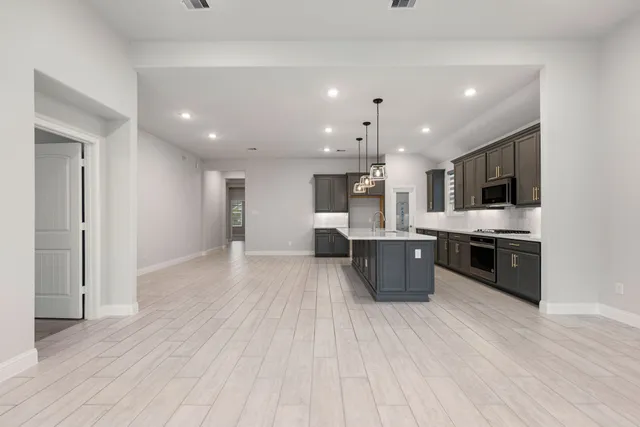 a large kitchen with stainless steel appliances kitchen island granite countertop a large counter top and wooden floors