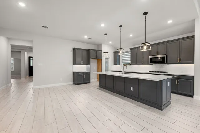 a large kitchen with stainless steel appliances kitchen island granite countertop a stove a sink and a refrigerator