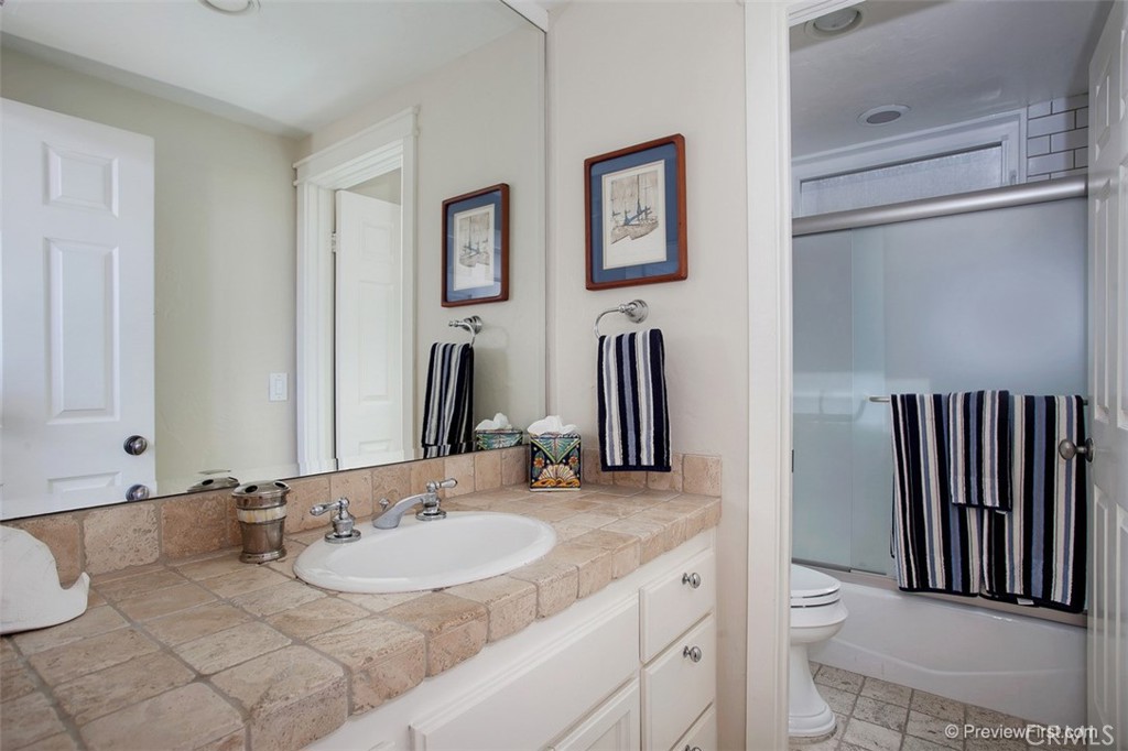441 Carnation Avenue Corona del Mar, CA 92625 - Photo 15 of 25 a bathroom with a granite countertop sink and a mirror