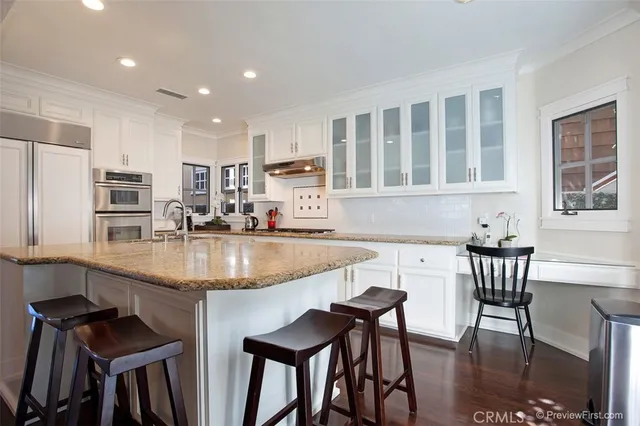 a kitchen with kitchen island granite countertop a table chairs sink and cabinets