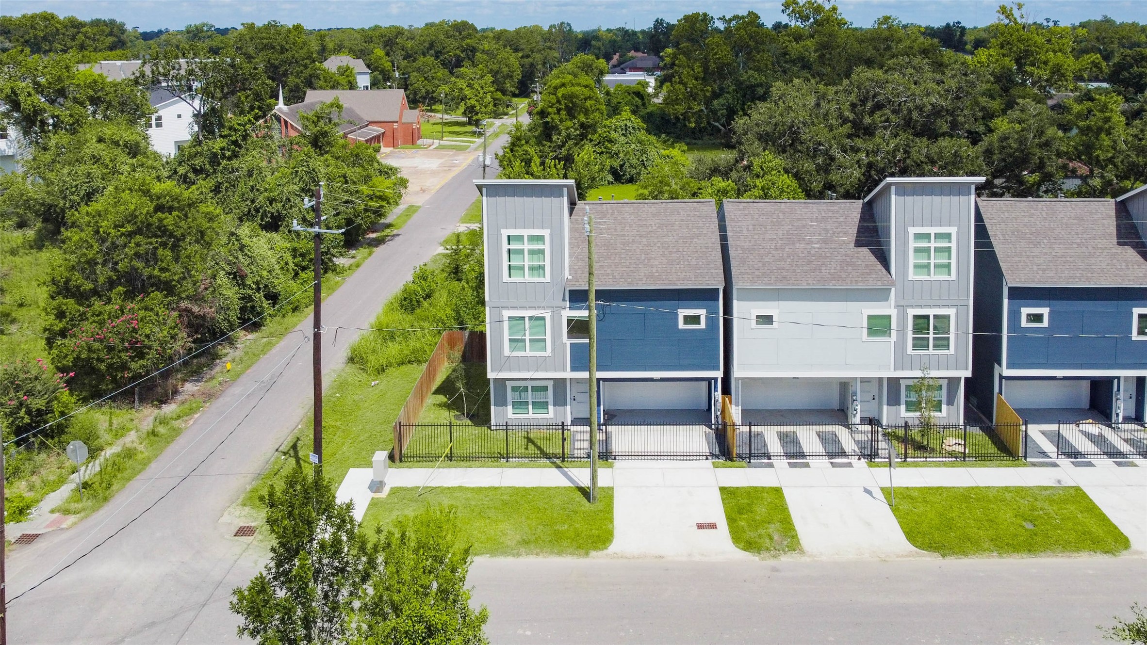 Welcome to Maybell Street where thoughtful design meets urban convenience. This aerial perspective showcases a row of contemporary homes, nestled in a peaceful, tree-lined neighborhood.