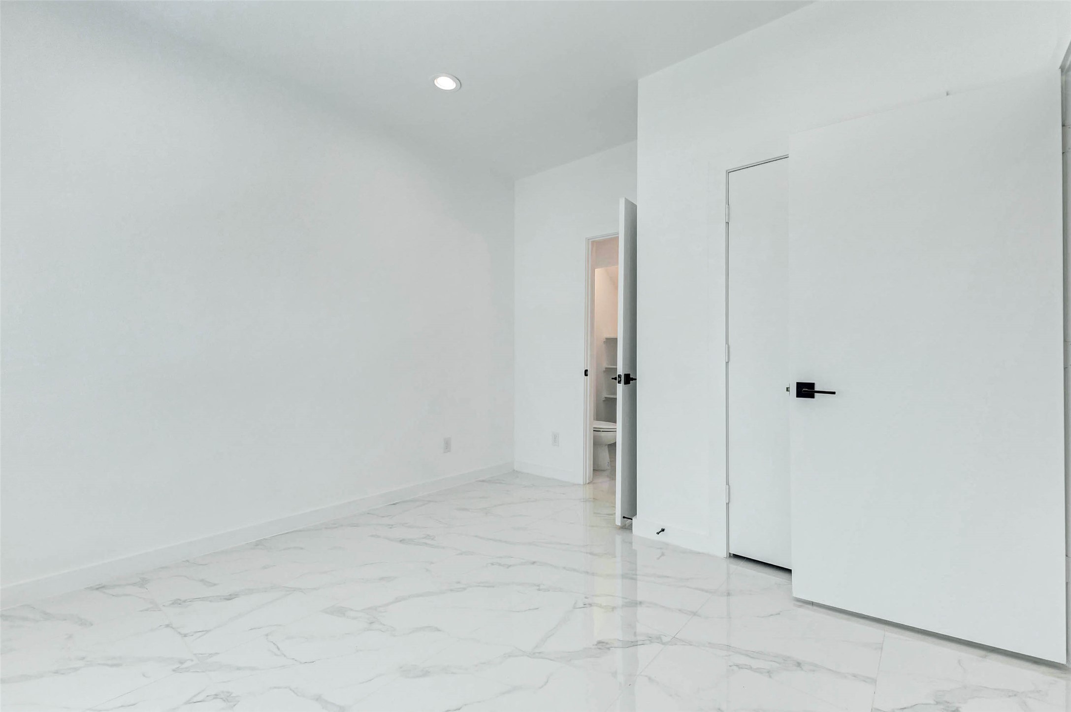 6017 Beall Street Houston, TX 77091 - Photo 21 of 33 Sleek, white, and refreshingly minimal. This secondary bedroom features large-format marble-look tile and recessed lighting perfect as a guest suite, home office, or flex space.