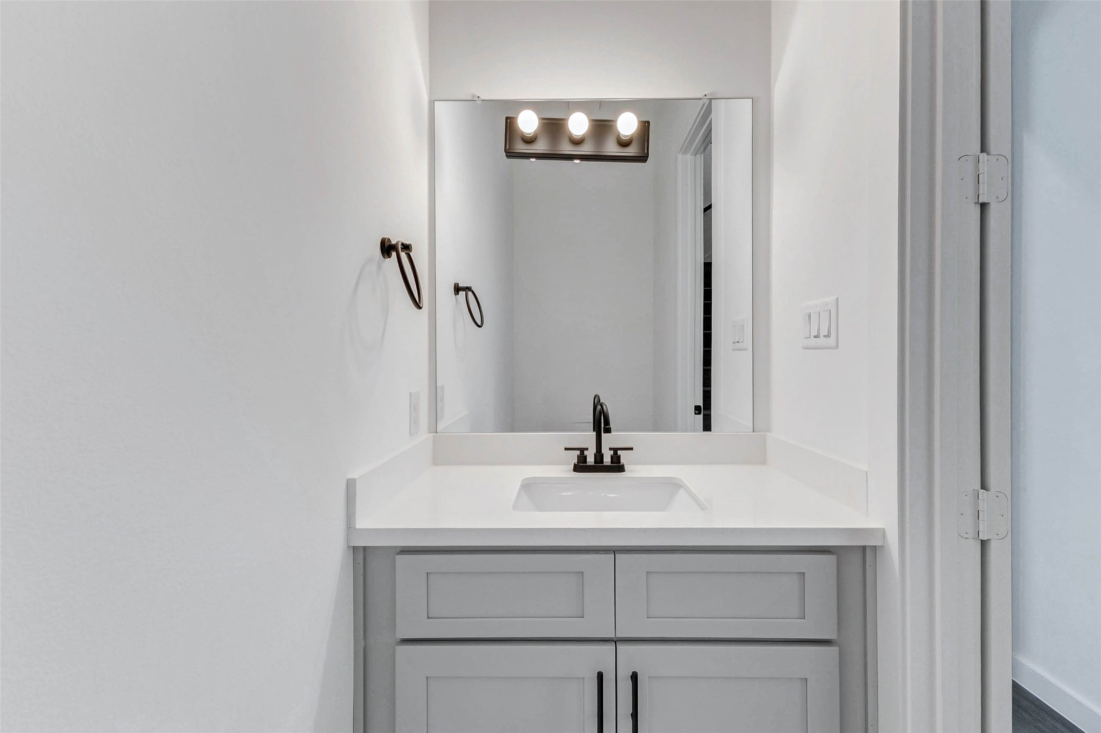 6017 Beall Street Houston, TX 77091 - Photo 26 of 33 Clean and contemporary, this full bath showcases a single-sink vanity with shaker-style cabinetry, black matte fixtures, and stylish wall lighting—perfect for daily routines or guest use.