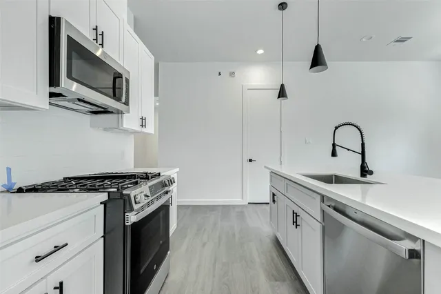 a kitchen with stainless steel appliances a sink dishwasher a stove and a microwave oven with wooden floor