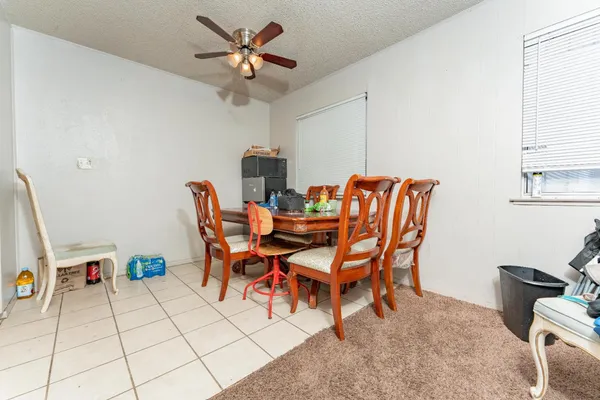 a dining room with furniture and a chandelier fan