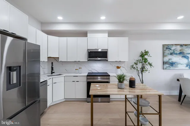 a kitchen with stainless steel appliances a stove a sink a microwave a refrigerator and cabinets