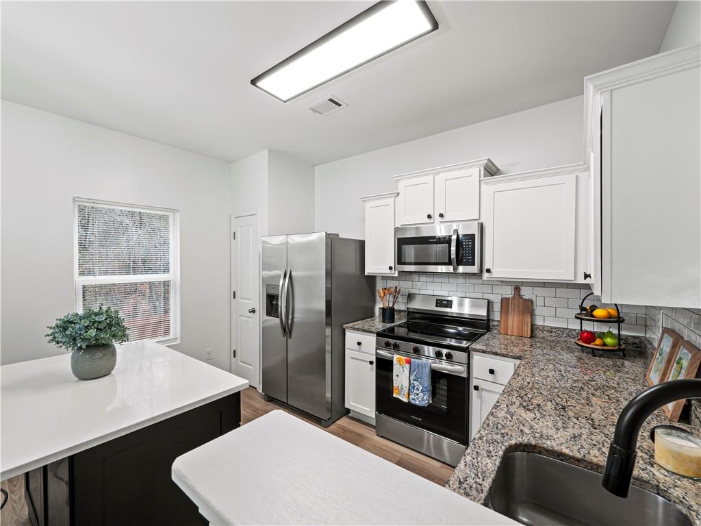 4334 Box Elder Path Gainesville, GA 30504 - Photo 12 of 39 a kitchen with stainless steel appliances a sink a microwave a refrigerator a stove and white cabinets