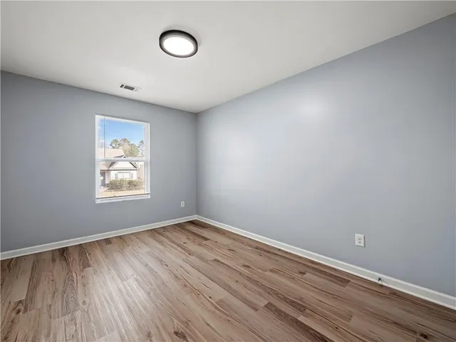 an empty room with wooden floor closet and windows