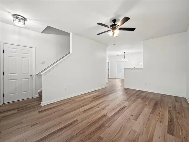 an empty room with wooden floor ceiling fan and windows