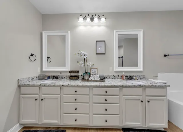 a bathroom with a granite countertop double vanity sink and mirror