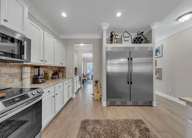 a kitchen with stainless steel appliances granite countertop a refrigerator a stove and a sink with wooden floor
