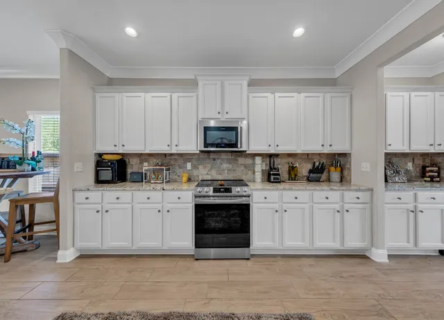a white kitchen with granite countertop stainless steel appliances