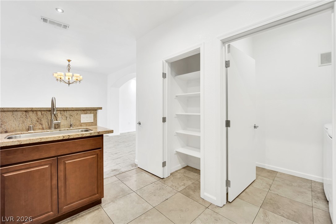 8725 West Flamingo Road, Unit 110 Las Vegas, NV 89147 - Photo 16 of 30 A functional kitchen sink area boasts granite counters, with convenient laundry and pantry access nearby.