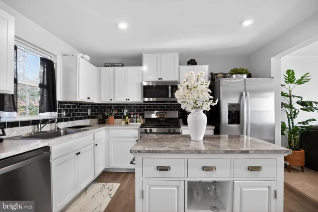 a kitchen with kitchen island granite countertop a stove and a white cabinets