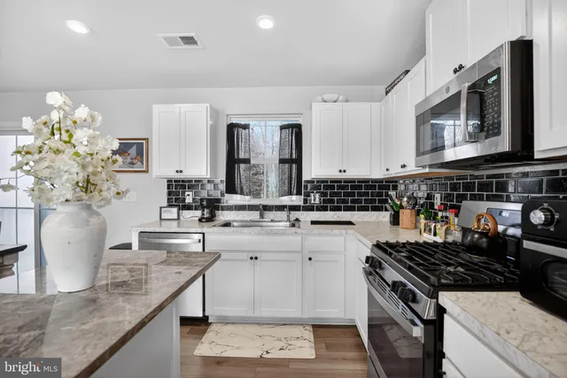 a kitchen with kitchen island granite countertop a sink a stove and cabinets