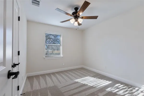 a view of an empty room and chandelier fan