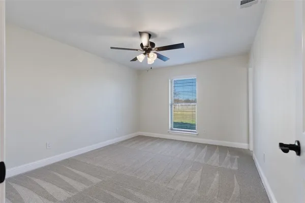 an empty room with windows and fan
