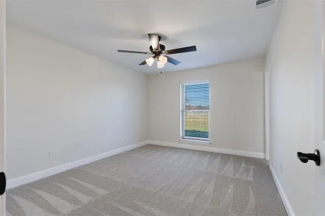 an empty room with windows and fan