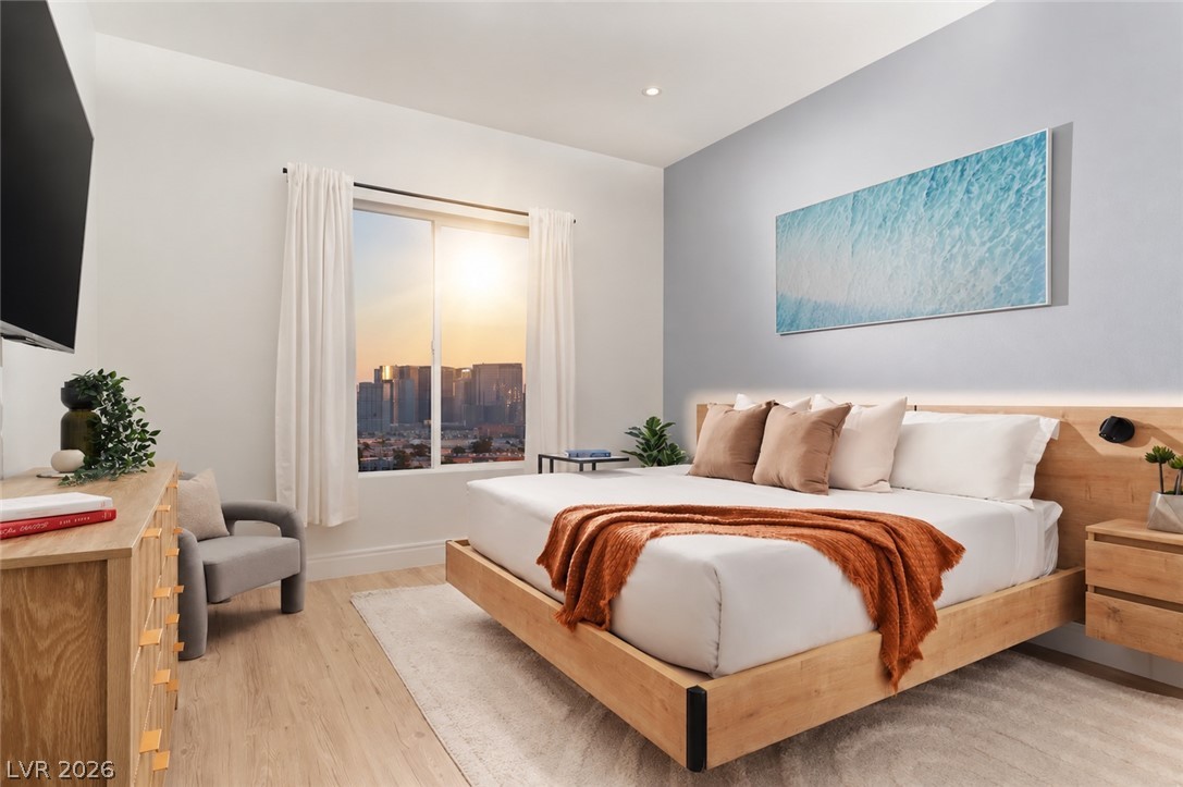 5050 West Russell Road, Unit 121 Las Vegas, NV 89118 - Photo 2 of 6 City skyline views stream through a large window into this modern bedroom with wood flooring.