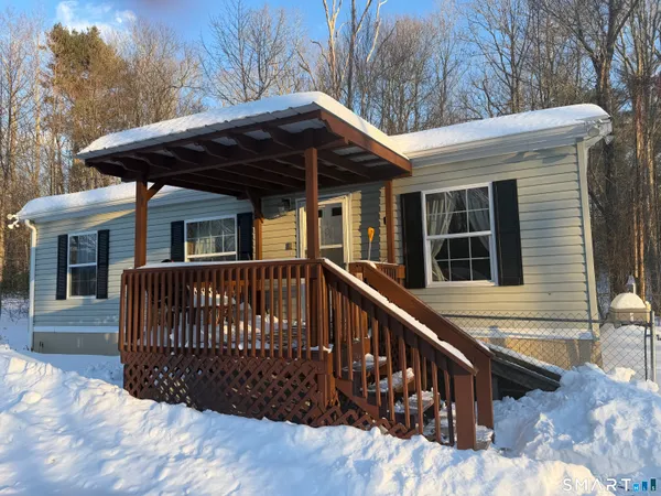 a view of house with wooden deck and furniture