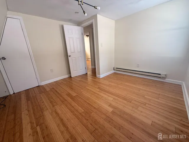 an empty room with wooden floor chandelier fan and windows