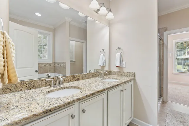 a bathroom with a granite countertop double vanity sink and mirror