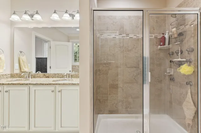 a bathroom with a granite countertop shower sink vanity and mirror