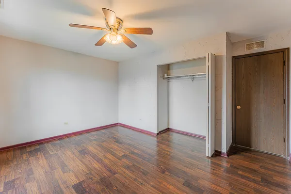 an empty room with wooden floor and a ceiling fan