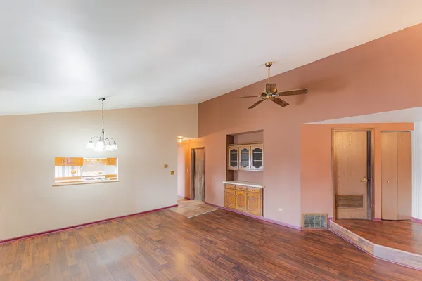 an empty room with wooden floor cabinet and windows