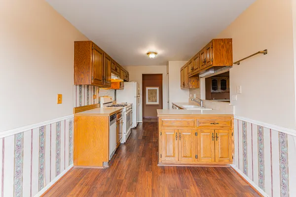 a kitchen with stainless steel appliances granite countertop a refrigerator a stove top oven a sink and dishwasher with wooden floor