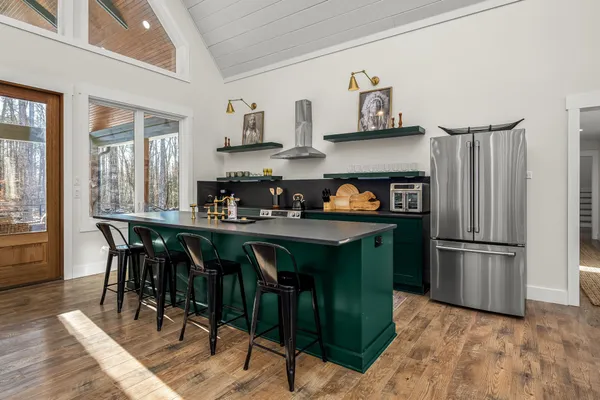 a kitchen with stainless steel appliances granite countertop a refrigerator a sink dishwasher a dining table and chairs with wooden floor