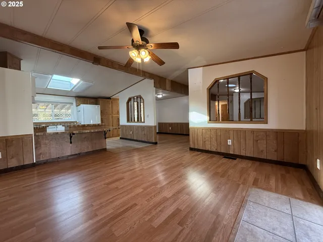 a living room with furniture and kitchen area with wooden floor
