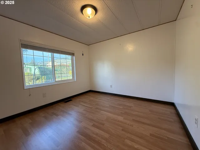 a view of an empty room with wooden floor and closet