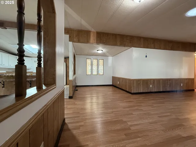 a view of an empty room with window and wooden floor