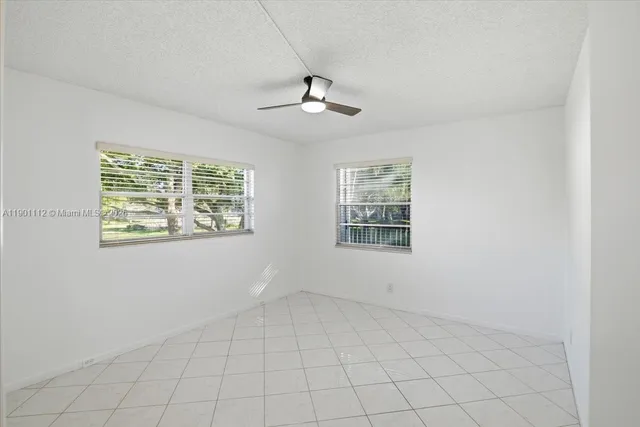 an empty room with windows and ceiling fan