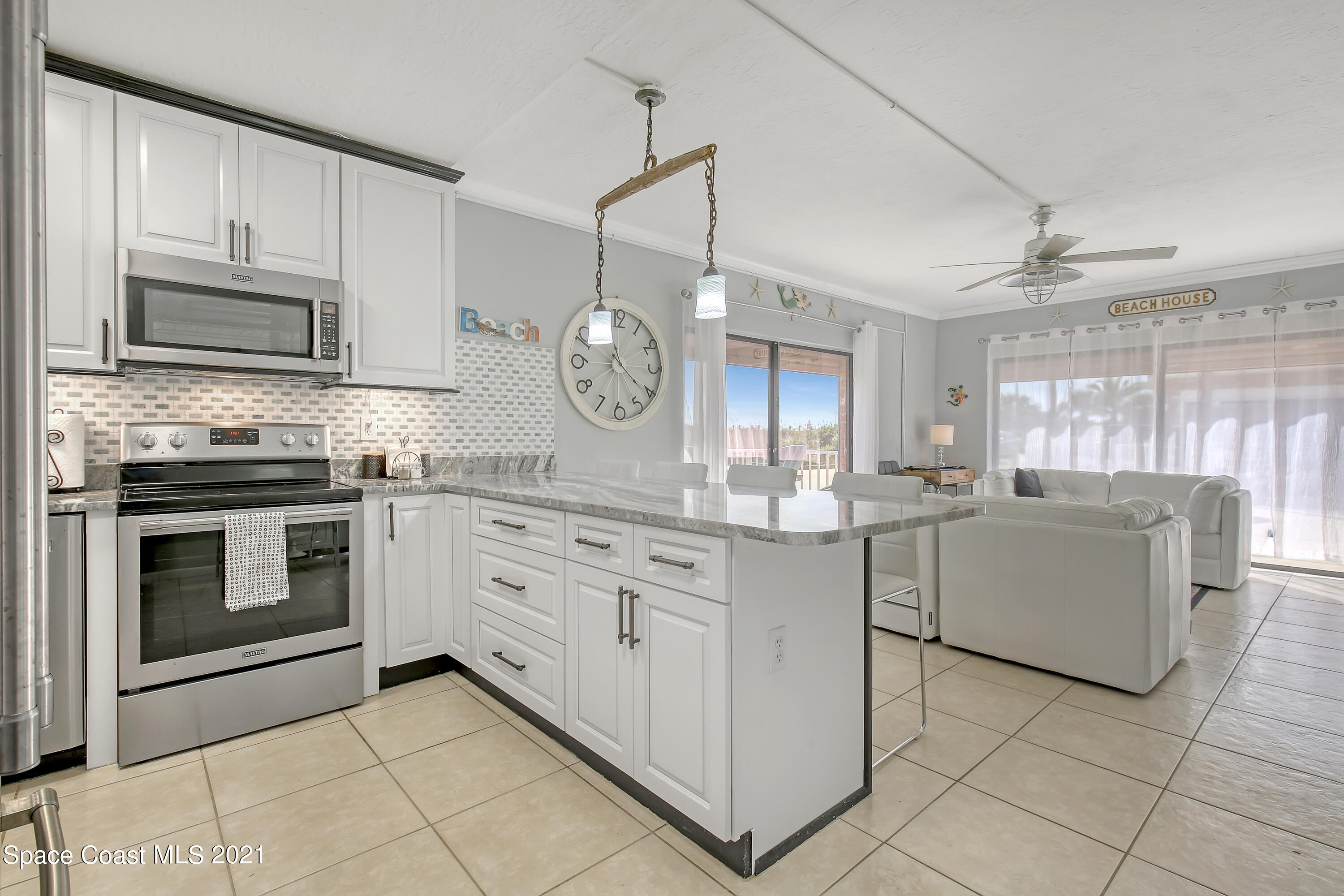 5000 Ocean Beach Boulevard, Unit C5 Cocoa Beach, FL 32931 - Photo 16 of 43 a kitchen with granite countertop white cabinets white stainless steel appliances with a sink and dishwasher