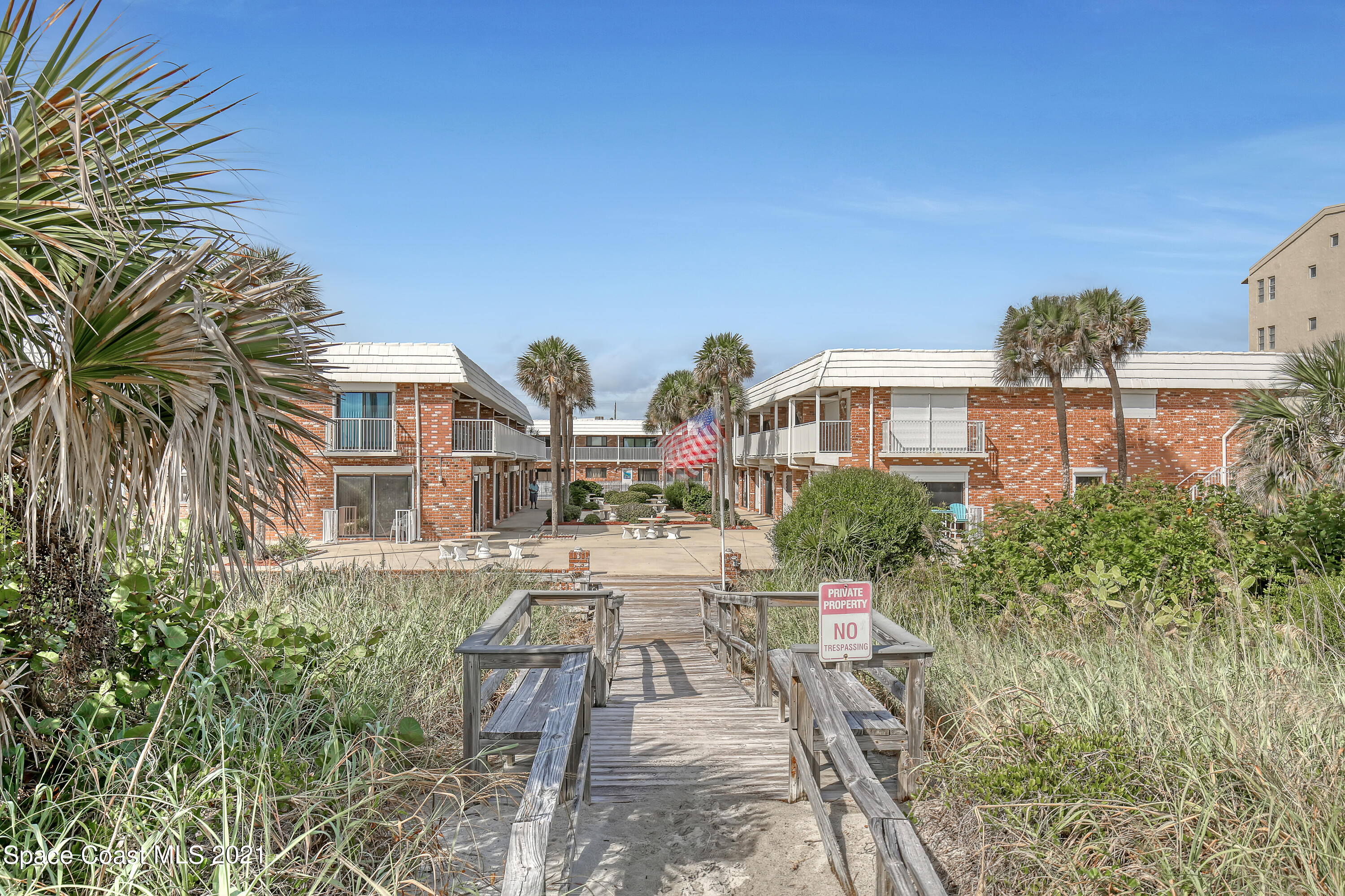 5000 Ocean Beach Boulevard, Unit C5 Cocoa Beach, FL 32931 - Photo 3 of 43 a view of a white house next to a yard with potted plants