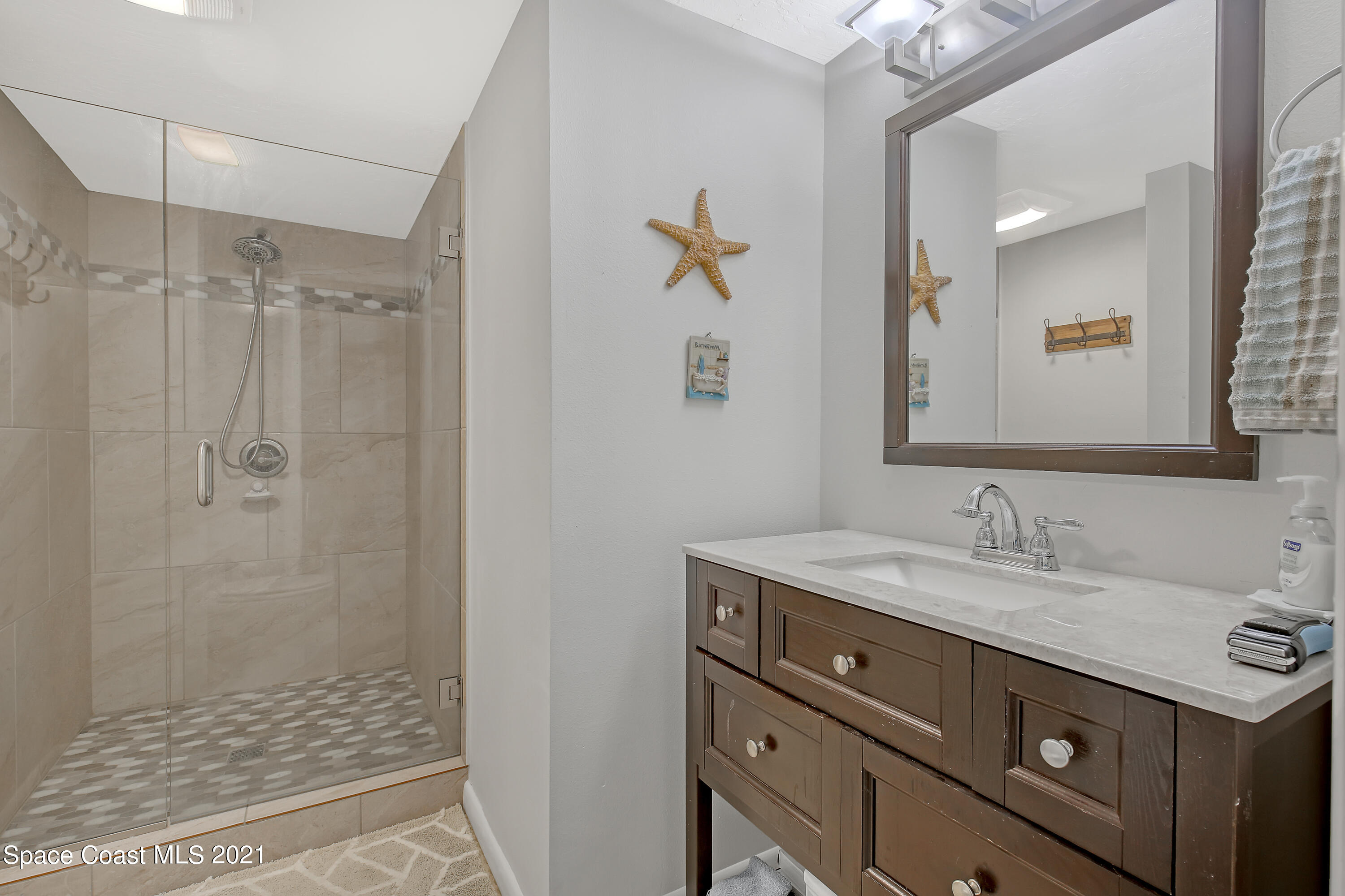 5000 Ocean Beach Boulevard, Unit C5 Cocoa Beach, FL 32931 - Photo 22 of 43 a bathroom with a granite countertop sink a mirror and shower