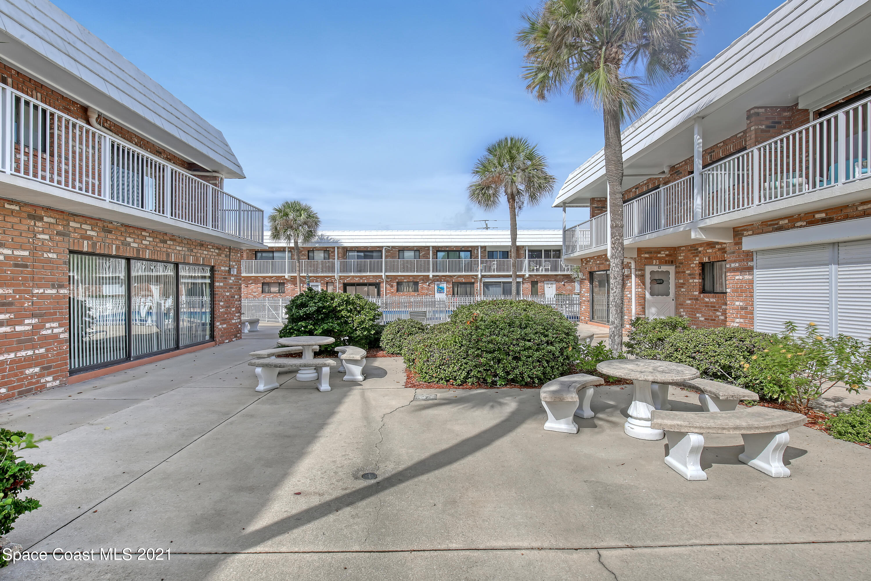 5000 Ocean Beach Boulevard, Unit C5 Cocoa Beach, FL 32931 - Photo 28 of 43 a view of a building with potted plants and a lawn chairs under an umbrella