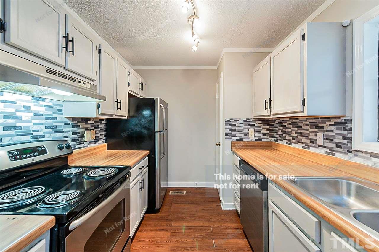 3622 Colchester Street, Unit 26 Durham, NC 27707 - Photo 4 of 16 a kitchen with stainless steel appliances kitchen island granite countertop a stove and a refrigerator