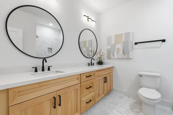 a bathroom with a toilet a double vanity and a mirror