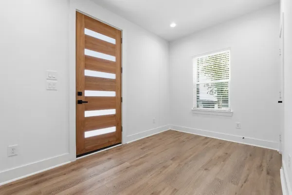 an empty room with wooden floor closet and windows