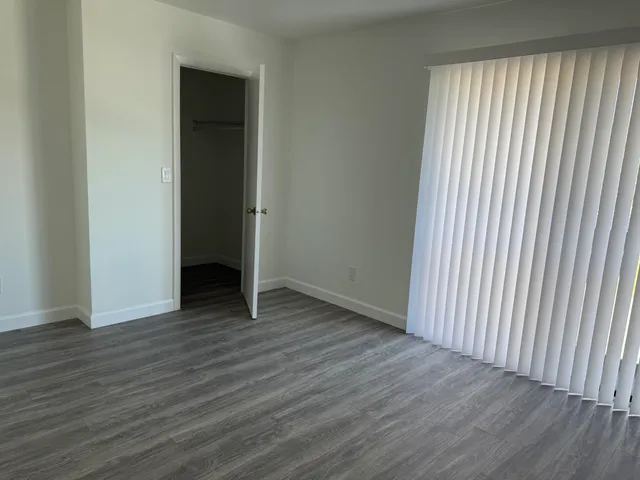 a view of an empty room with a window and wooden floor