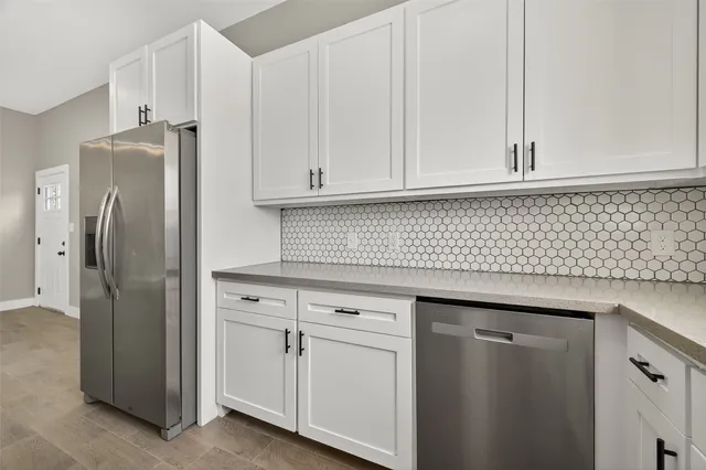 a kitchen with stainless steel appliances granite countertop white cabinets and refrigerator
