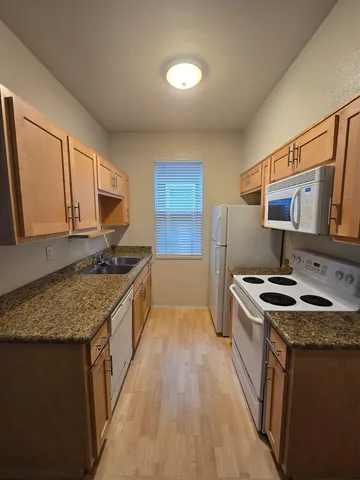 a kitchen with stainless steel appliances granite countertop a stove a sink dishwasher and a refrigerator