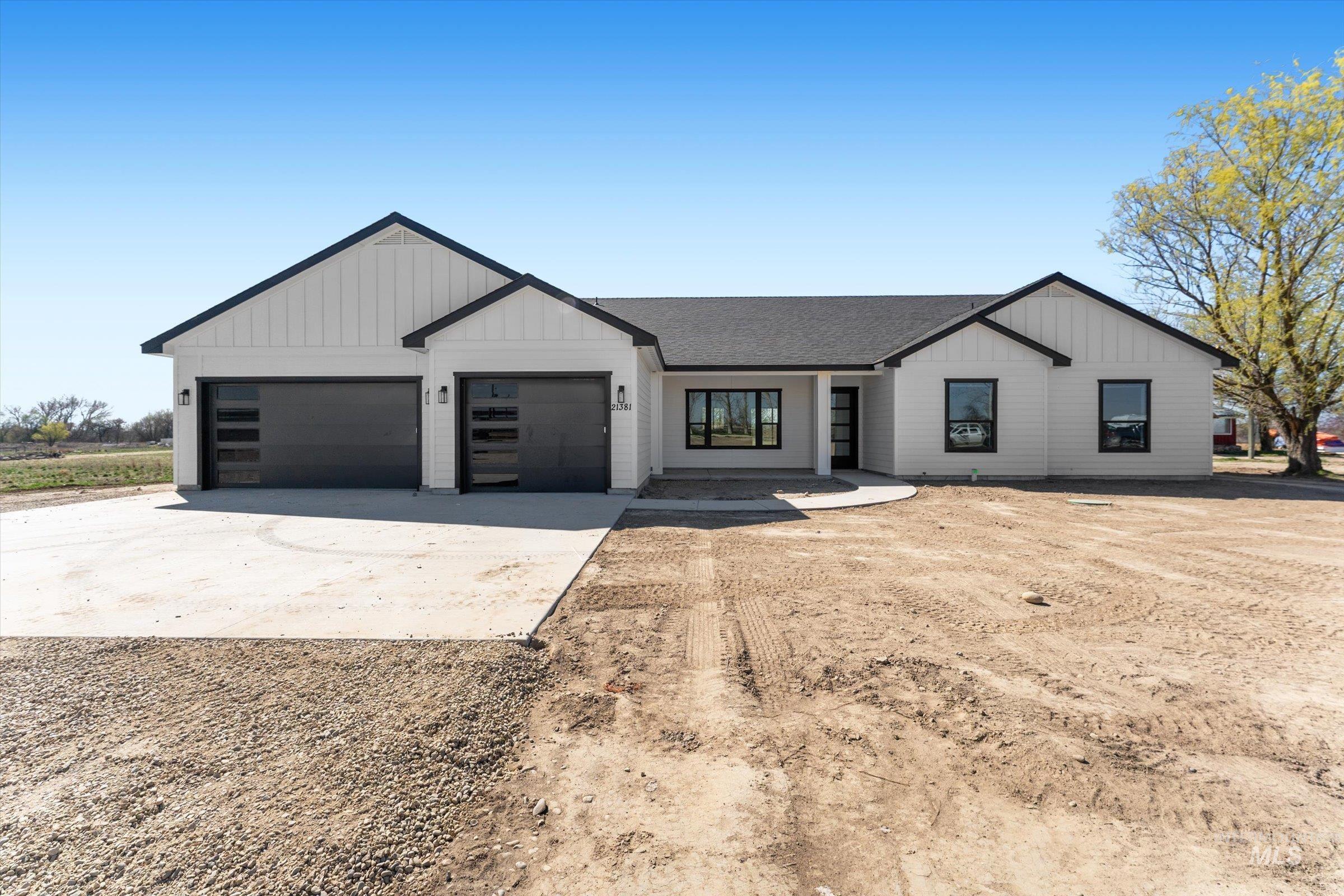 26219 Reed Lane Wilder, ID 83676 - Photo 1 of 35 Modern farmhouse featuring concrete driveway, a garage, a shingled roof, covered porch, and board and batten siding