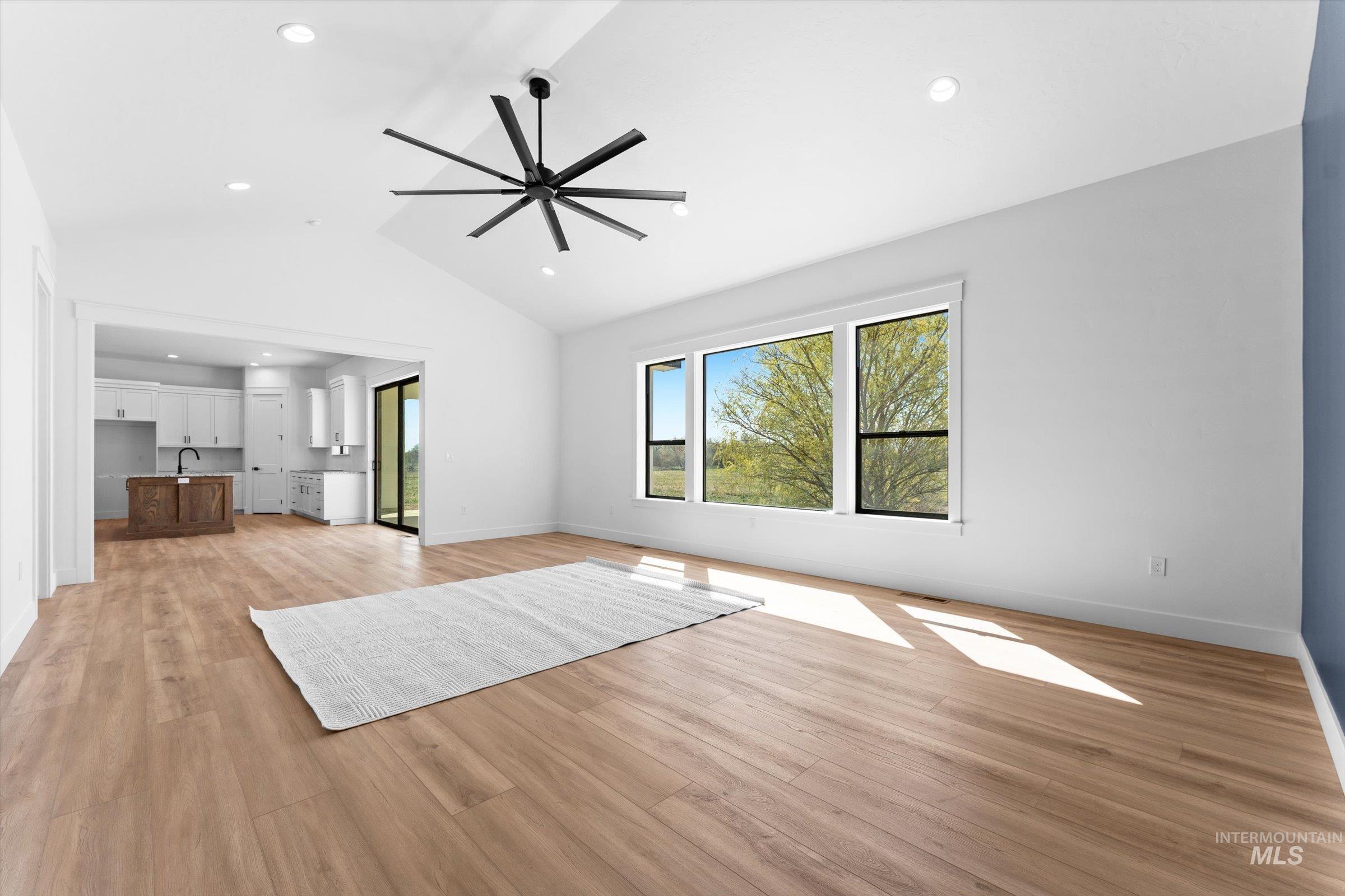 26219 Reed Lane Wilder, ID 83676 - Photo 10 of 35 Unfurnished living room with a ceiling fan, light wood finished floors, vaulted ceiling, and recessed lighting