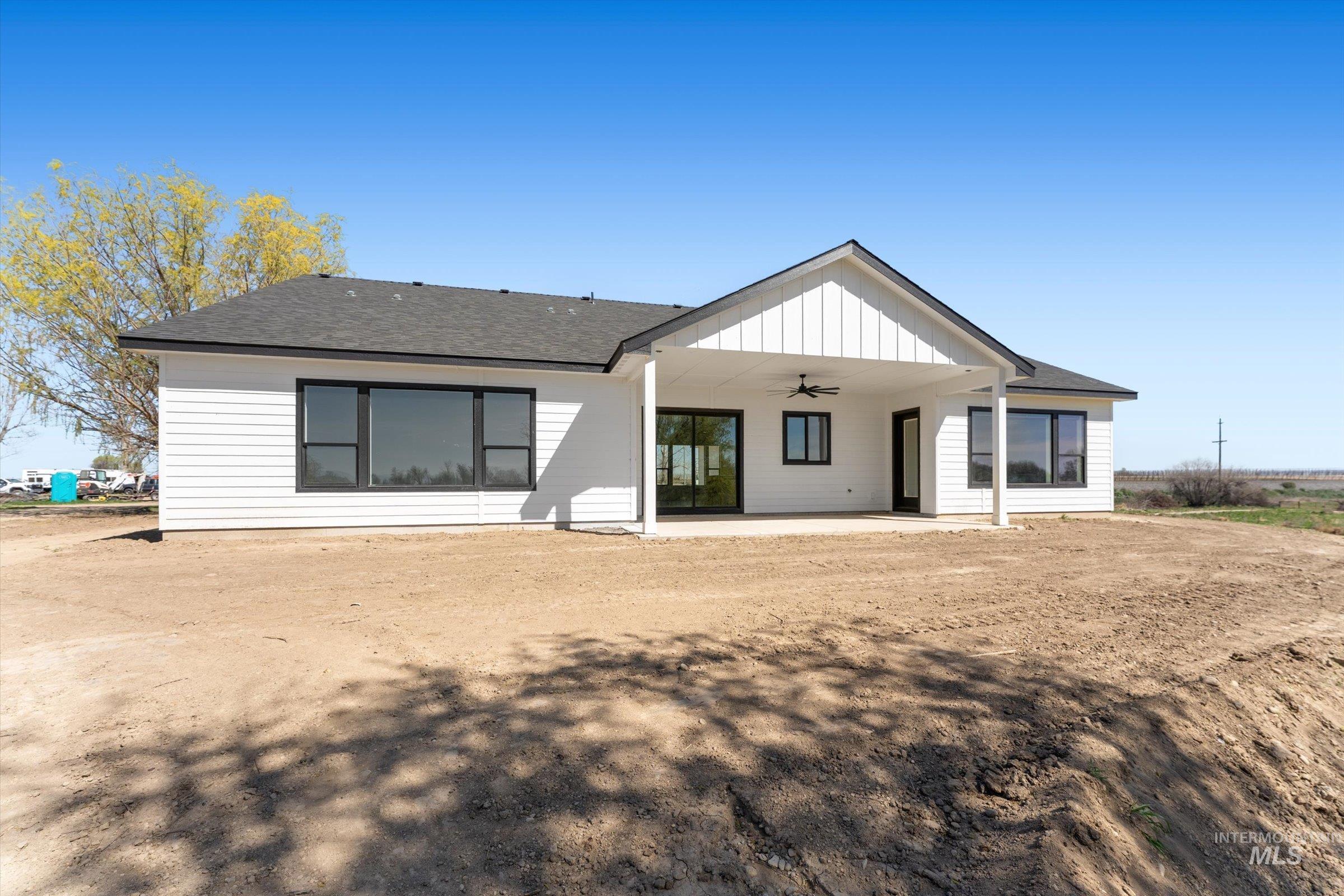 26219 Reed Lane Wilder, ID 83676 - Photo 31 of 35 Rear view of house with a shingled roof, a patio area, a ceiling fan, and board and batten siding